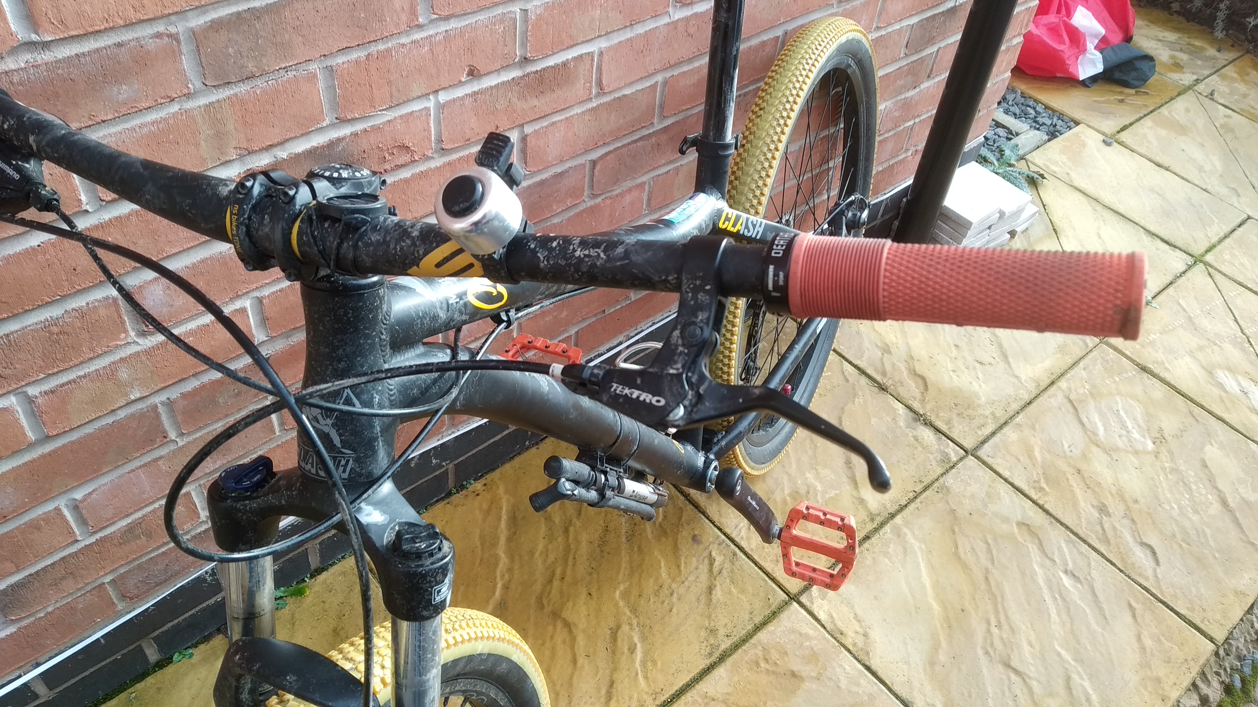 The front end of a slightly muddy bike. The cables run a mess through the front and down the bike.