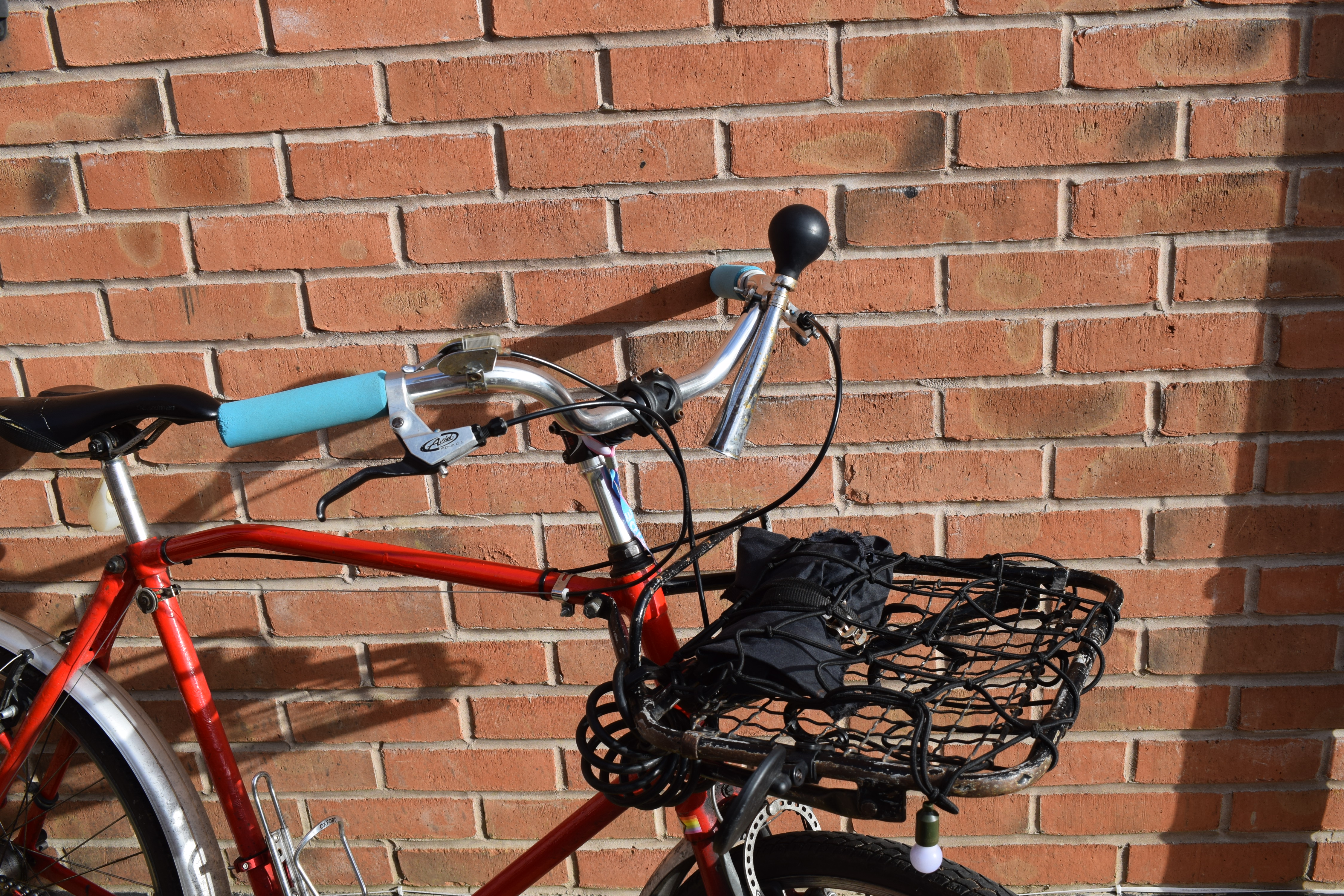 A pic of the front of the bike, showing a metal rack with a wire base, and an elastic net over the top, with a small roll of cloth held down by straps to the rack