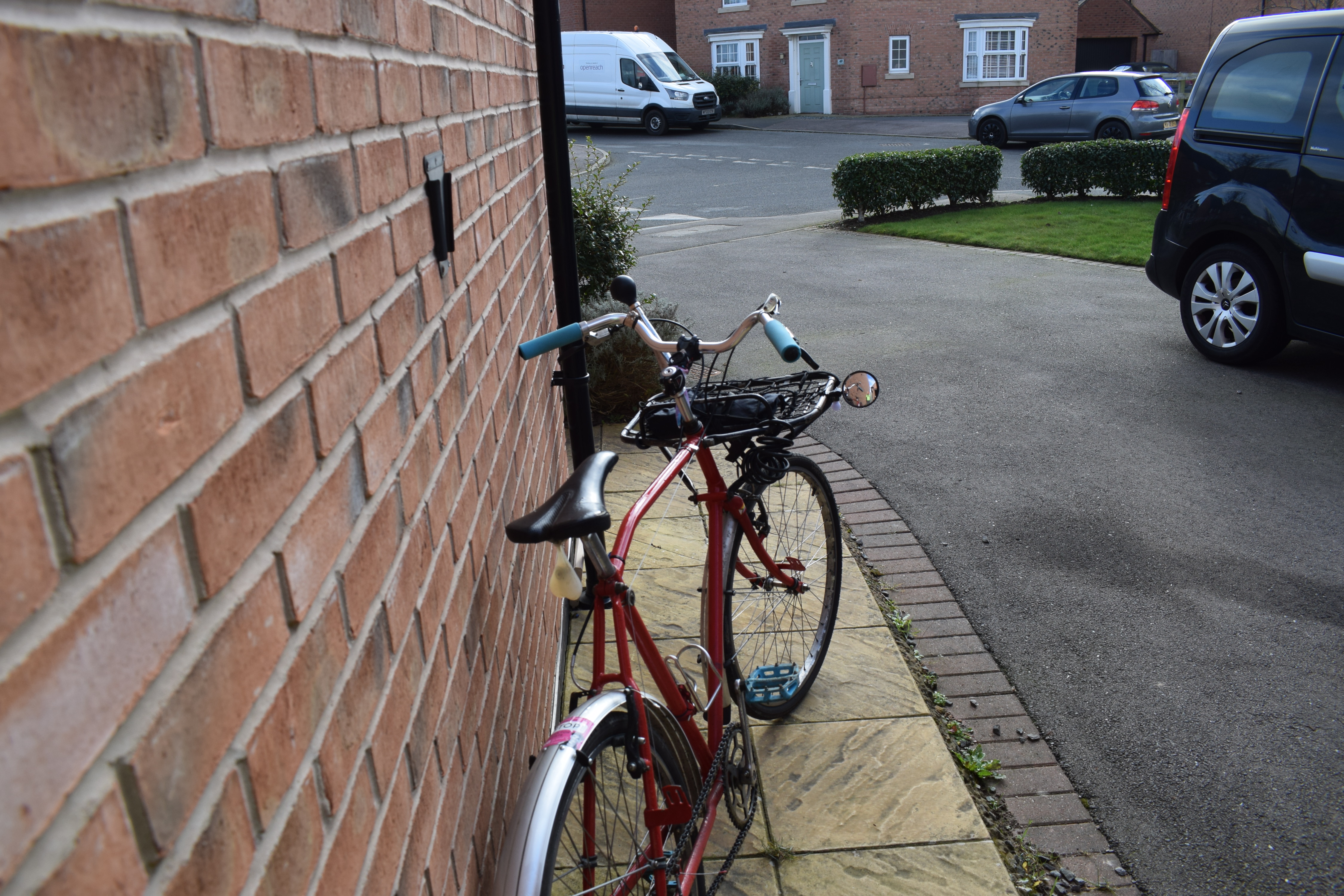 A view from the rear of a red bike as it leans against the wall