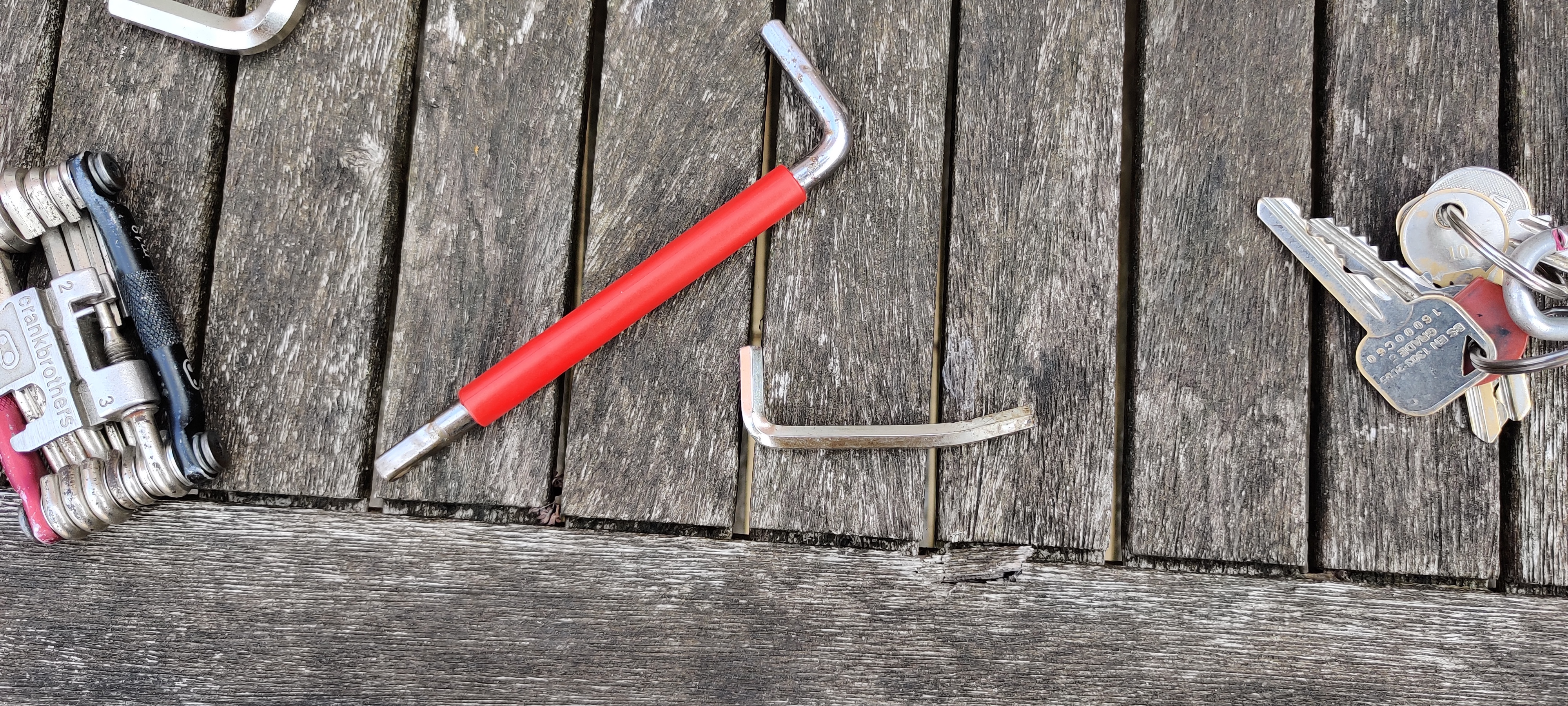 A bent allen key on a table next to some other tools