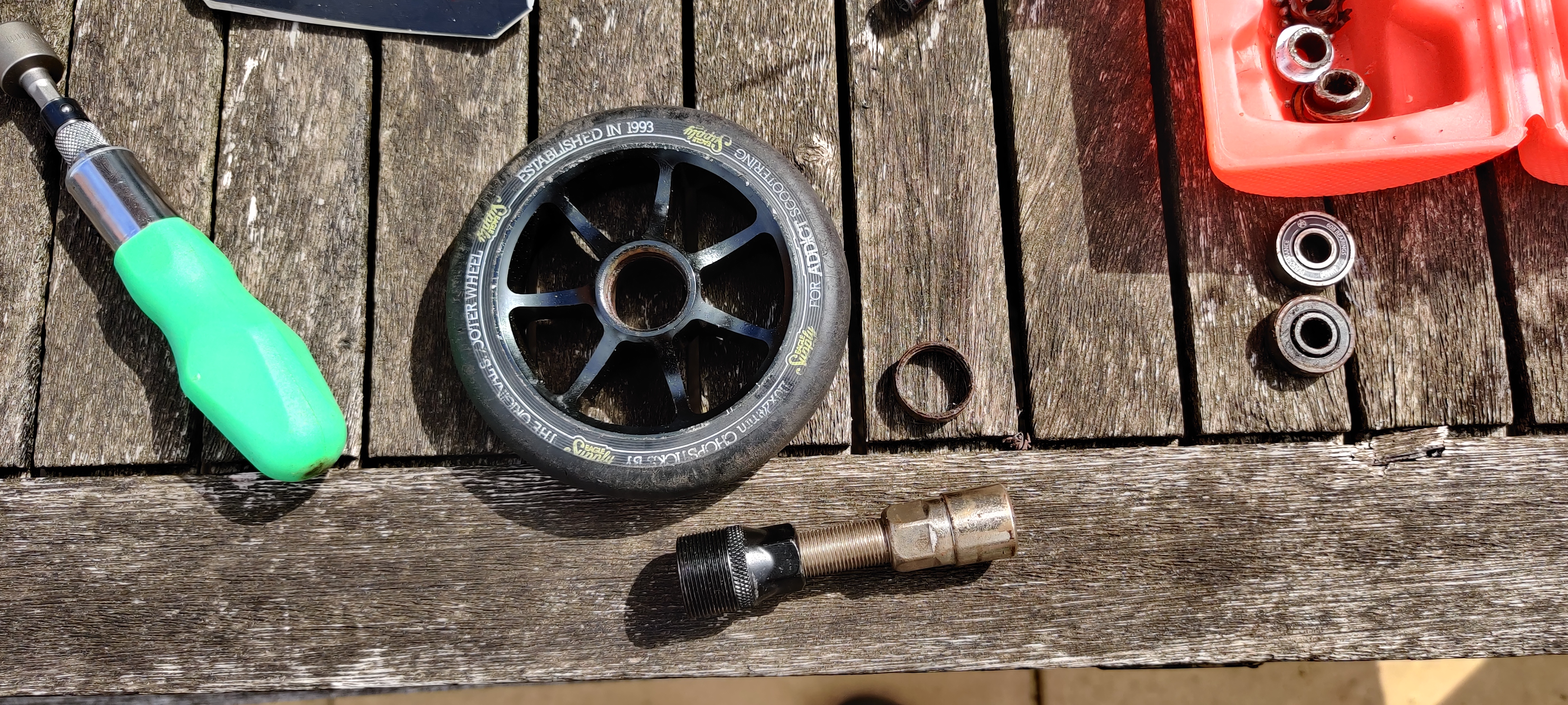A bicycle crank puller next to the outer race of a bearing, and a wheel completely free of bearing parts