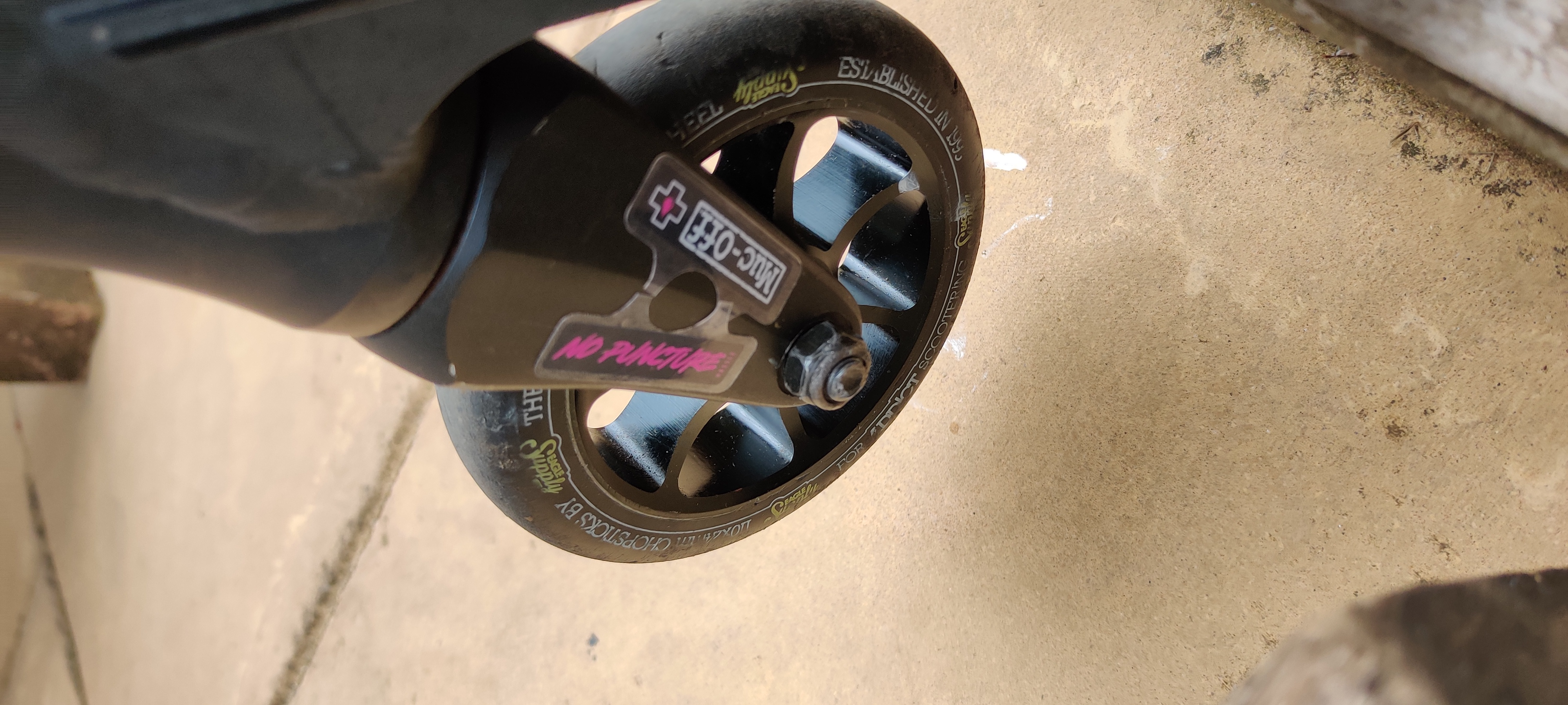 A close up of the front wheel and fork with a "no puncture" mucoff sticker wrapped on it