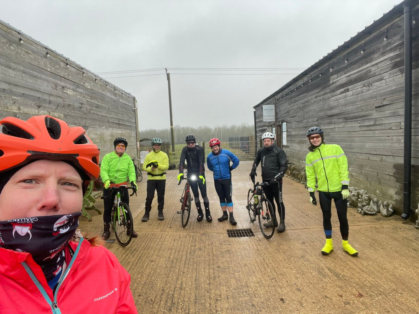 A poicture of a group of cyclists, one taking the selfie in orange, 3 yellow, 2 black, 1 blue. It's cold, we're smiling outwardly.