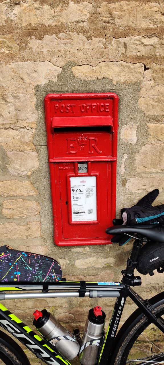 A red postbox in a rough brick wall. Collection time 9:00am weekdays, 7:00am Saturdays